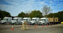 Line of trucks used for training lined up in front of Cypress Truck Lines CDL School.